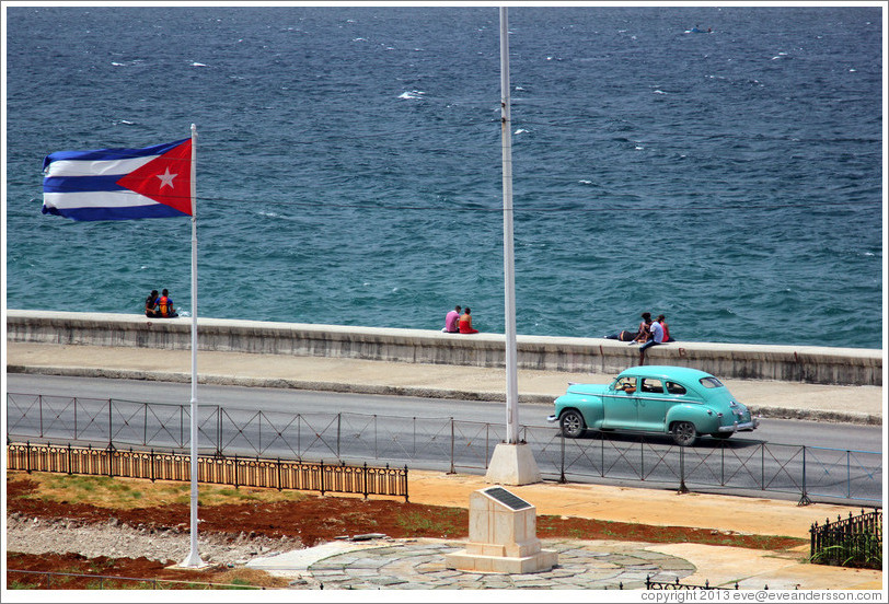 Cuban flag and a blue car on the Malec&oacute;n.