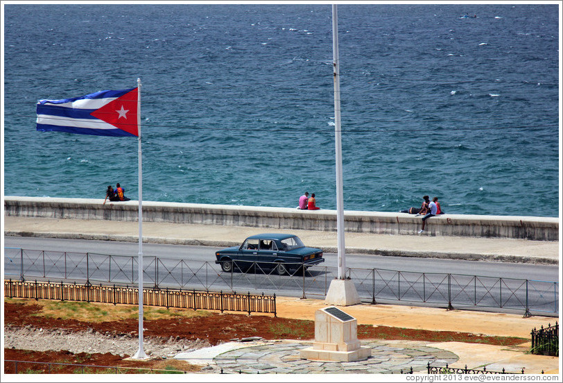 Cuban flag and a dark green car on the Malec&oacute;n.