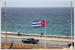 Cuban flag and a green and black car on the Malec&oacute;n.