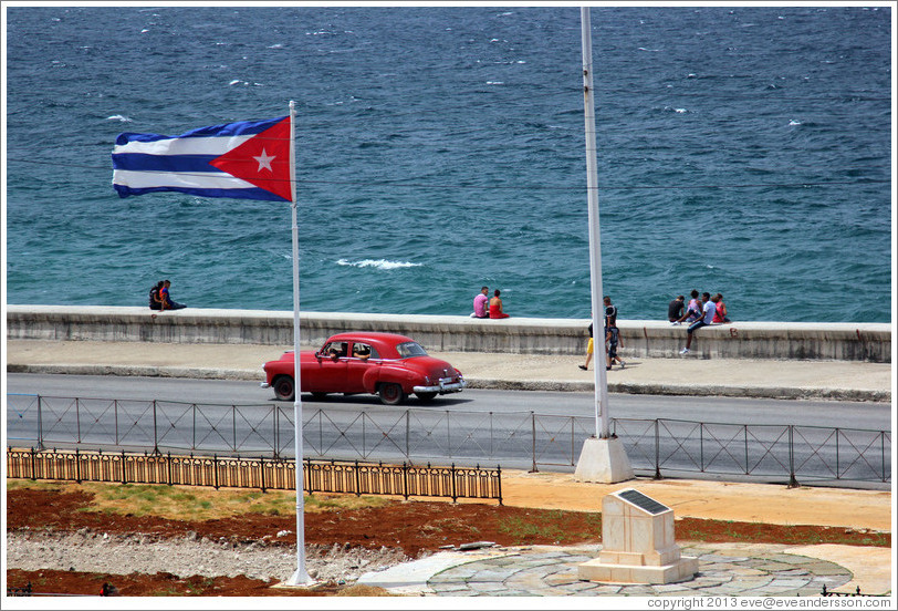 Cuban flag and a red car on the Malec&oacute;n.