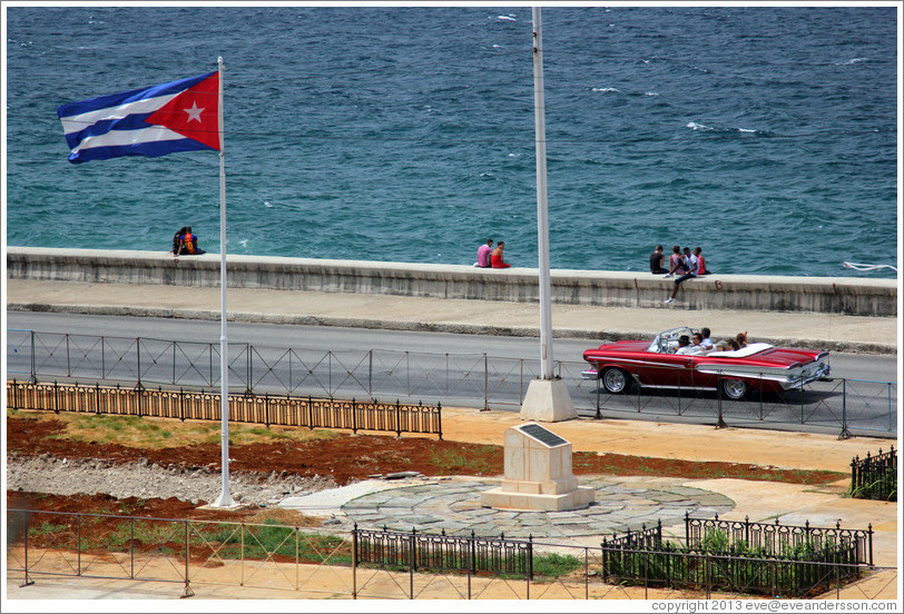 Cuban flag and a red convertible on the Malec&oacute;n.