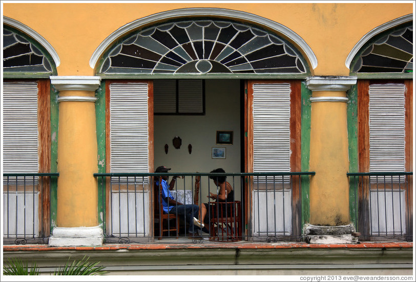 Family sitting near an open window, Plaza de Armas, Old Havana.