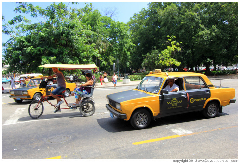 Bicycle taxi and black and white auto taxi, corner of Paseo del Prado and Calle Obrapia.