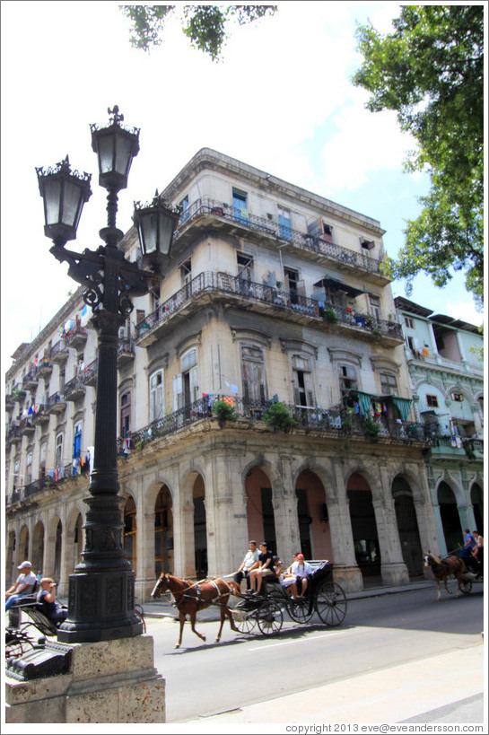 Horse drawn carriage passing a beige building, Paseo del Prado.