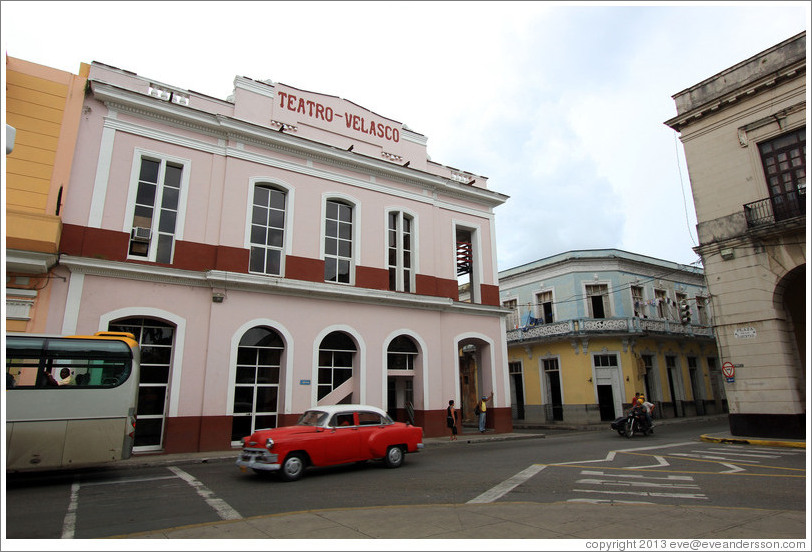 Red and white car passing Teatro Velasco near Parque de la Libertad (Liberty Park).