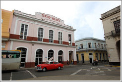 Red and white car passing Teatro Velasco near Parque de la Libertad (Liberty Park).