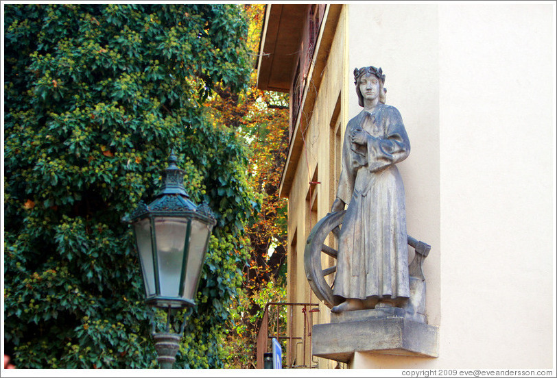 Sculpture of a woman with a wheel and an axe, on the side of a building, Kampa, Mal?trana.