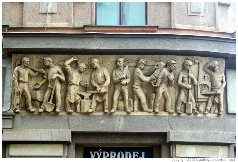 Nine laborers, with the caption "EXPORT IMPORT" carved into a building on Pansk?Nov?&#283;sto.