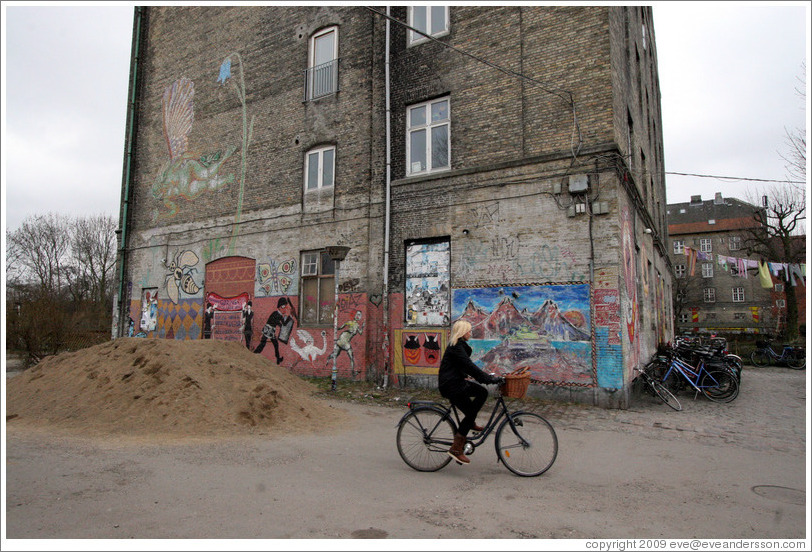 Bicyclist riding past building with painted wall.