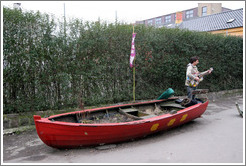 Guitar player, near a wooden boat painted with the three dots of Christiania.