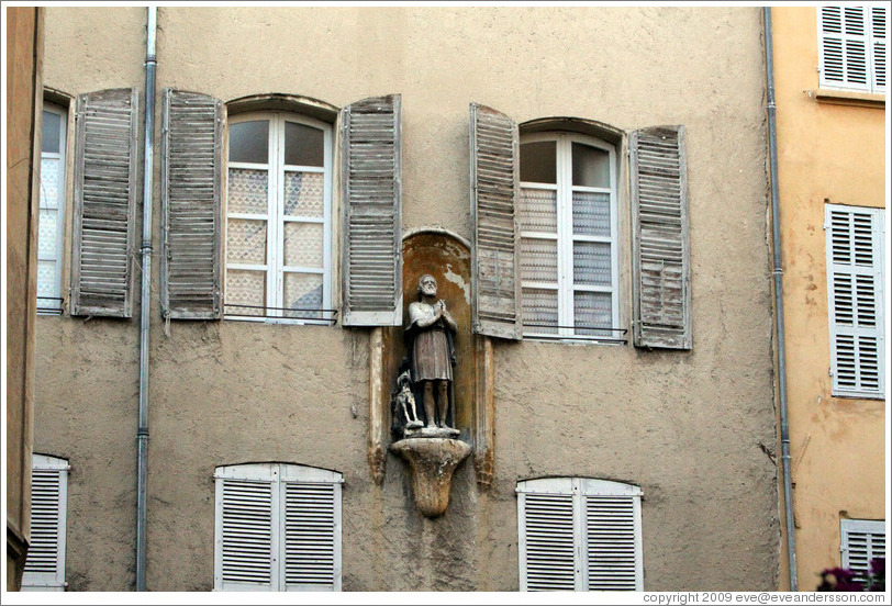 Oratory depicting a man and a dog.  A pigeon sits on the dog's head.  Rue Espariat at Rue de la Masse.  Old town.