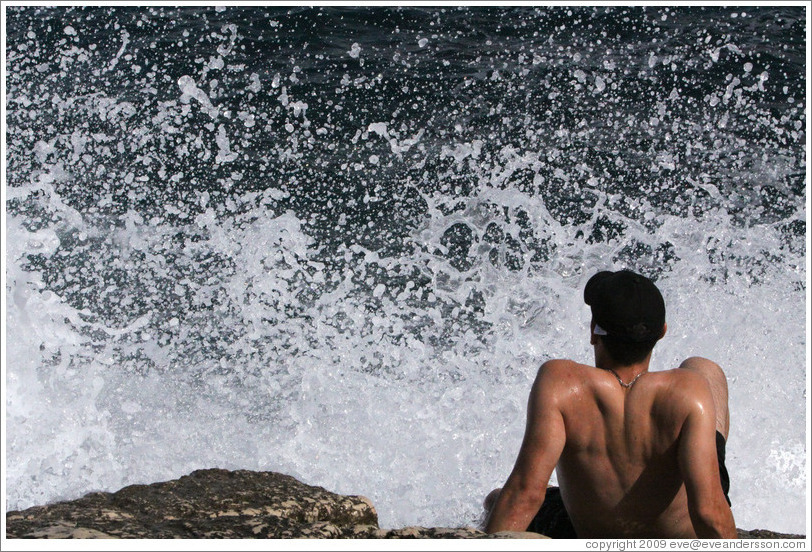 Man about to be drenched by water splashing off the rocks.  Calanque de Port-Miou.