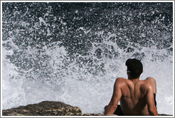 Man about to be drenched by water splashing off the rocks.  Calanque de Port-Miou.