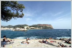 Sunbathers on the calanques, with a lighthouse in the background.