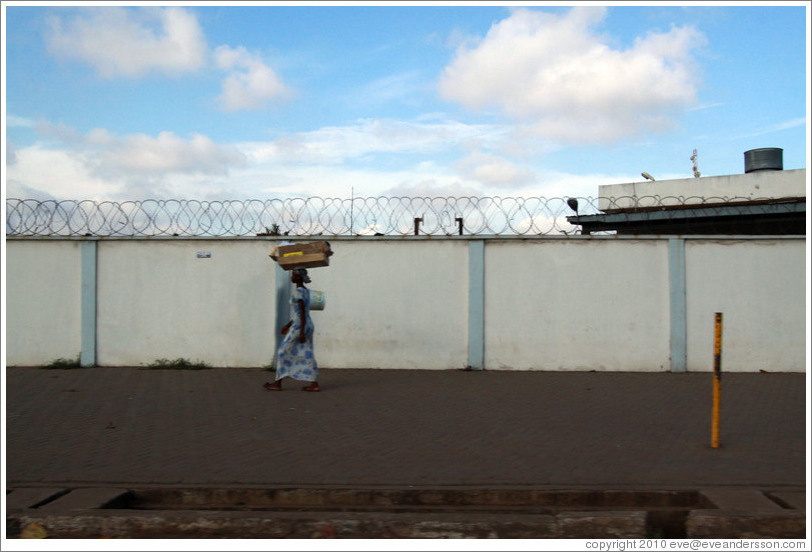 Lady balancing a box on her head.