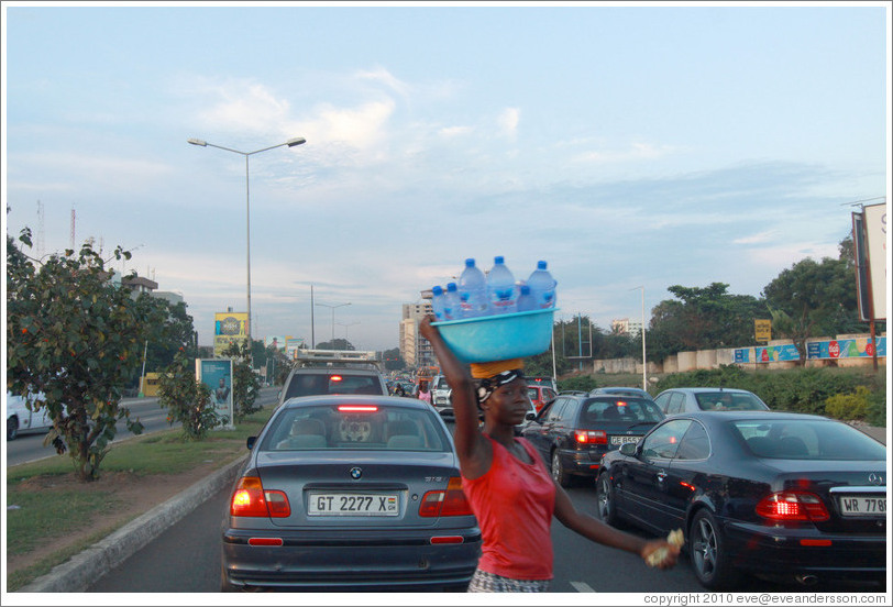 Woman selling bottles of water on the road.