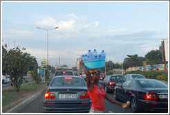Woman selling bottles of water on the road.