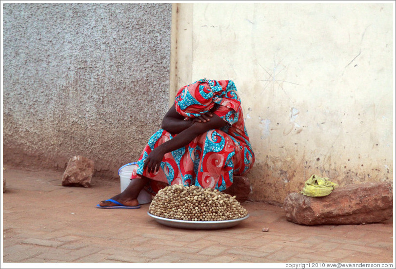 Woman with peanuts for sale, resting.