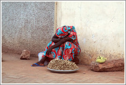 Woman with peanuts for sale, resting.
