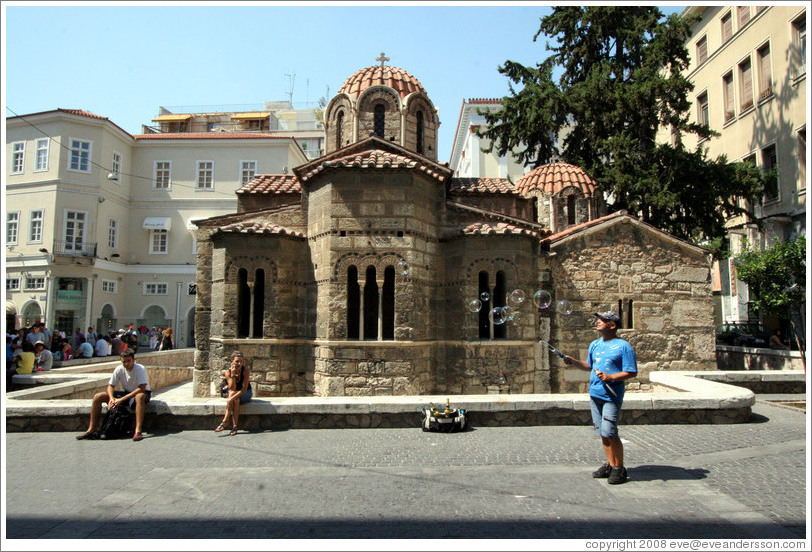 Man blowing bubbles in front of the Church of Panaghia Kapnikarea (&#917;&#954;&#954;&#955;&#951;&#963;&#943;&#945; &#964;&#951;&#962; &#928;&#945;&#957;&#945;&#947;&#943;&#945;&#962; &#922;&#945;&#960;&#957;&#953;&#954;&#945;&#961;&#941;&#945;&#962;), one of the oldest churches in Athens.