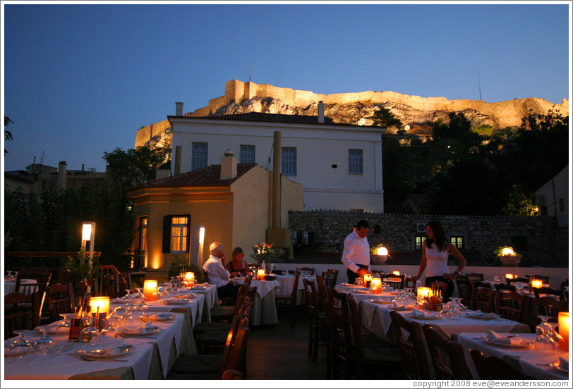 &#917;&#955;&#945;&#953;&#945; restaurant.  Rooftop dining area with the Acropolis (&#913;&#954;&#961;&#972;&#960;&#959;&#955;&#951;) behind it, at night.