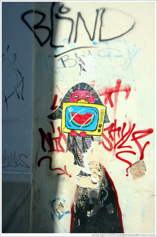 Graffiti depicting a girl holding a television set displaying a bitten watermelon slice.