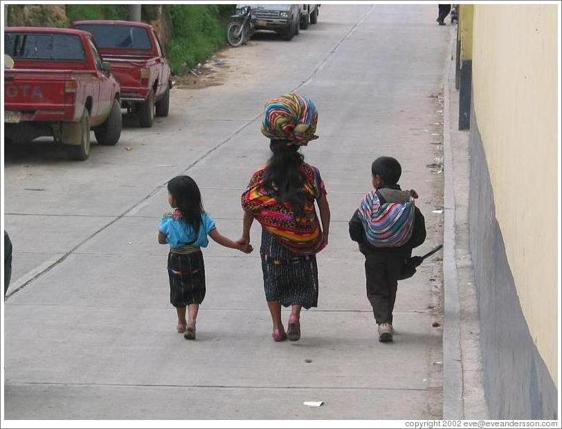 Woman balancing bag with two kids.
