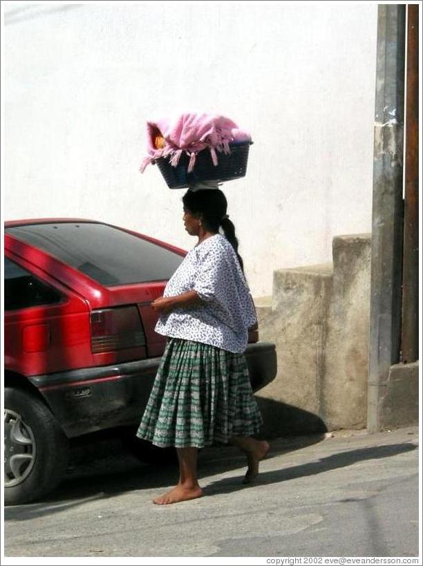 Woman carrying basket on head.