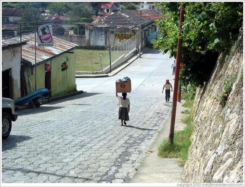 Woman carrying box on head.