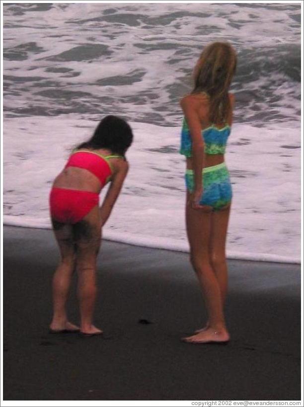 Two girls watching the baby turtles making their way to sea.