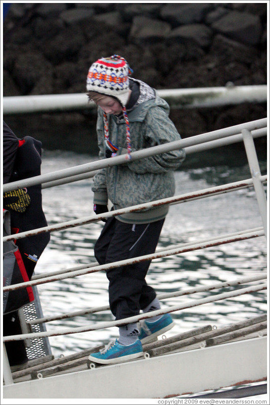 Child in Icelandic hat walking down ramp to boat.