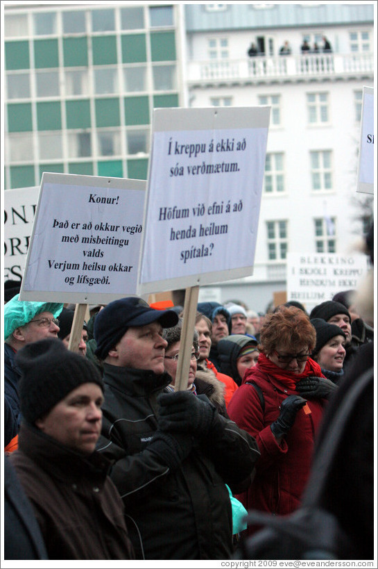 Reykjavik protest.  The left sign says "Konur! ?? a?kur vegi??sbegitingu valds; Verjum heilsu okkar og l?g?." ("Women! We are under attack by abuse of power; Let's defend our health and living standards.")   The right sign says "?kreppu ?kki a?a ver?um. H?fum vi?ni ??nda heilum sp?la?" ("In a depression one should not waste valuables. Can we afford to throw away a whole hospital?")