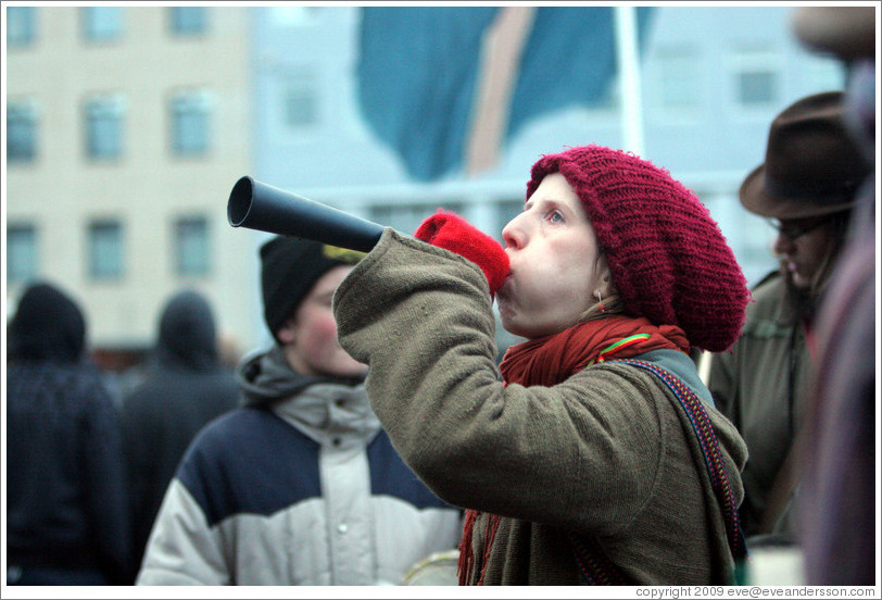 Reykjavik protest.  Woman blowing forn.