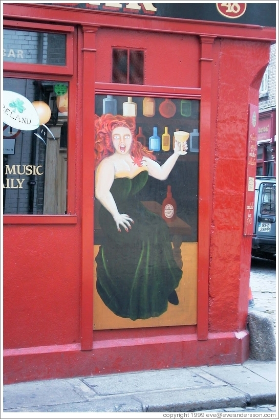 Painting of a fiery redhead enjoying the drink -- on a pub in Temple Bar, Dublin.