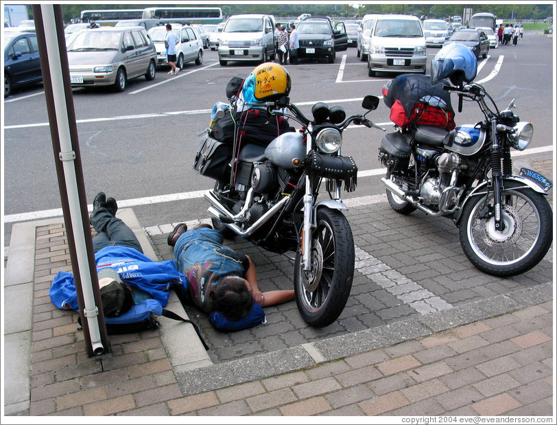Expressway rest stop.  Sleeping motorcyclists.