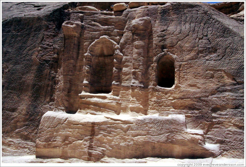 Stone wall with votive niches carved into it.