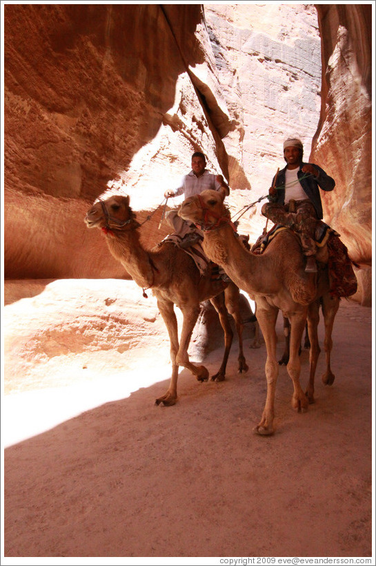 Two men riding camels in As-Siq, a narrow natural gorge.