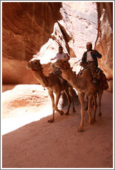 Two men riding camels in As-Siq, a narrow natural gorge.