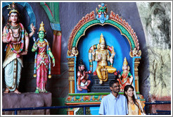 Two people in front of statues, Batu Caves.