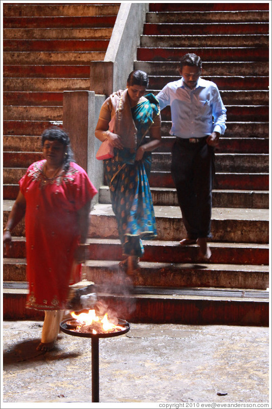 People descending steps toward fire, Batu Caves.