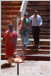 People descending steps toward fire, Batu Caves.