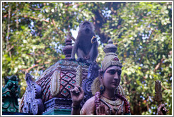 Monkey sitting above statue, stairway, Batu Caves.