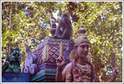 Monkey sitting above statue, stairway, Batu Caves.