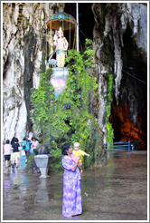 Woman and baby in front of statue of woman and peacock, Batu Caves.