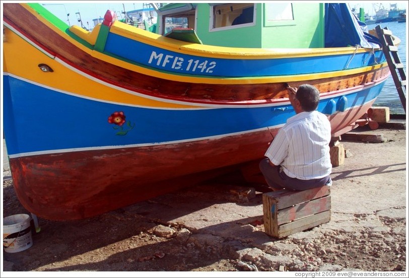 Man varnishing his boat next to Marsaxlokk Bay.