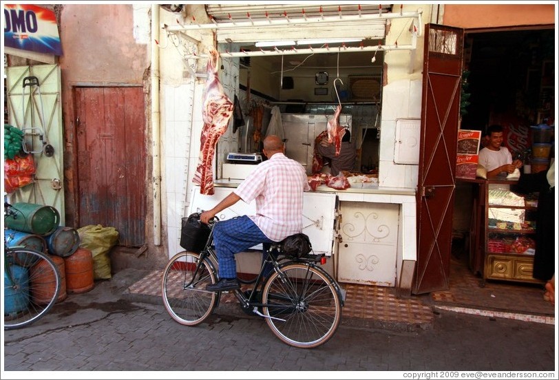 Man on a bicycle in front of a butcher in the Medina.