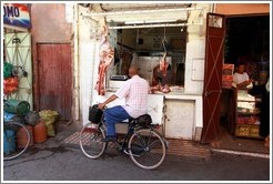 Man on a bicycle in front of a butcher in the Medina.