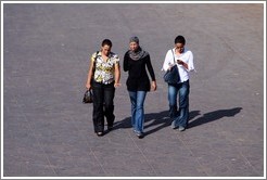 Three women walking, two without headdresses.  Jemaa el Fna.