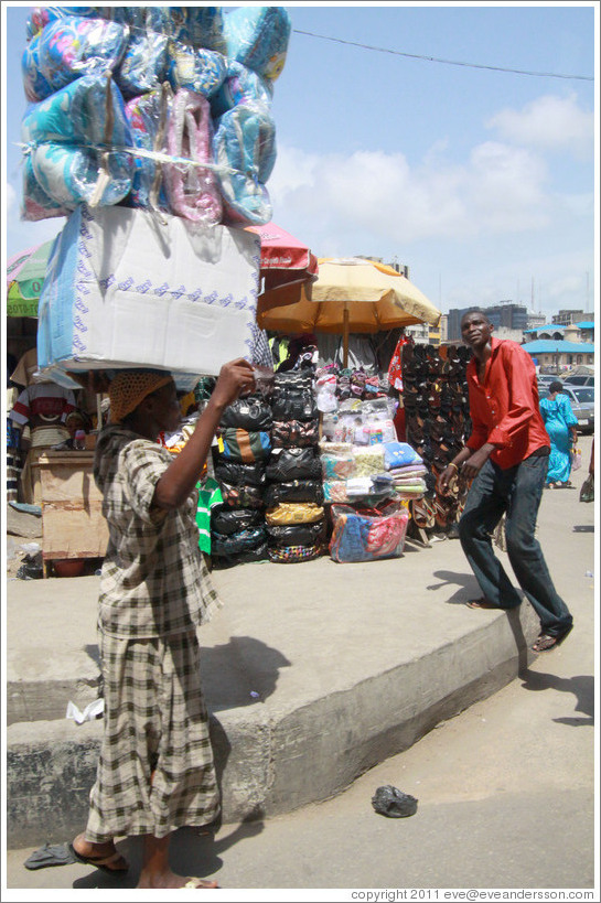 Woman carrying blankets on her head.