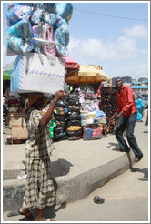 Woman carrying blankets on her head.